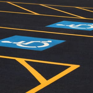 black asphalt parking lot with yellow striping and blue handicap markings